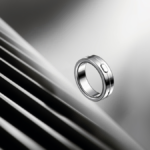 Silver ring-shaped device with a small button floating against a blurred, striped background.
