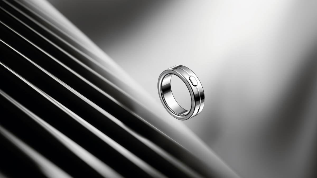 Silver ring-shaped device with a small button floating against a blurred, striped background.