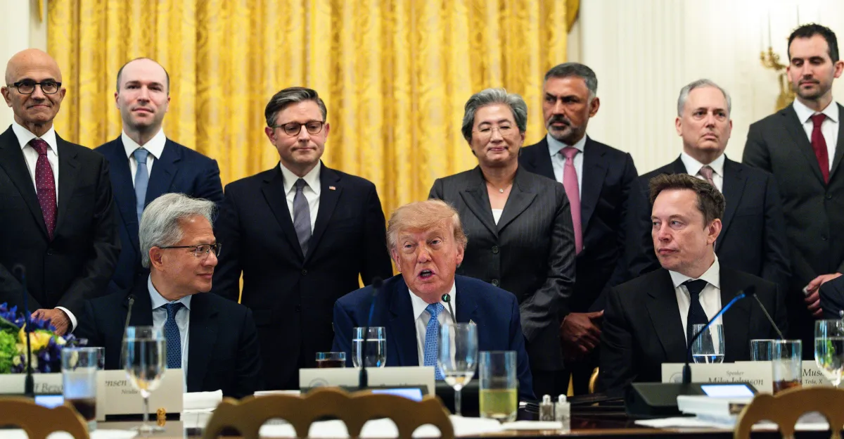 A group of executives and officials seated and standing around a table with microphones and nameplates in a formal setting.