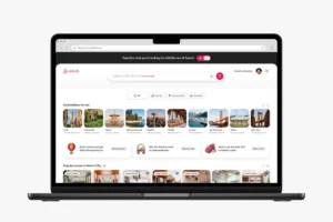 Laptop screen showing Airbnb's website with AI search bar, travel destinations, and promotional offers.