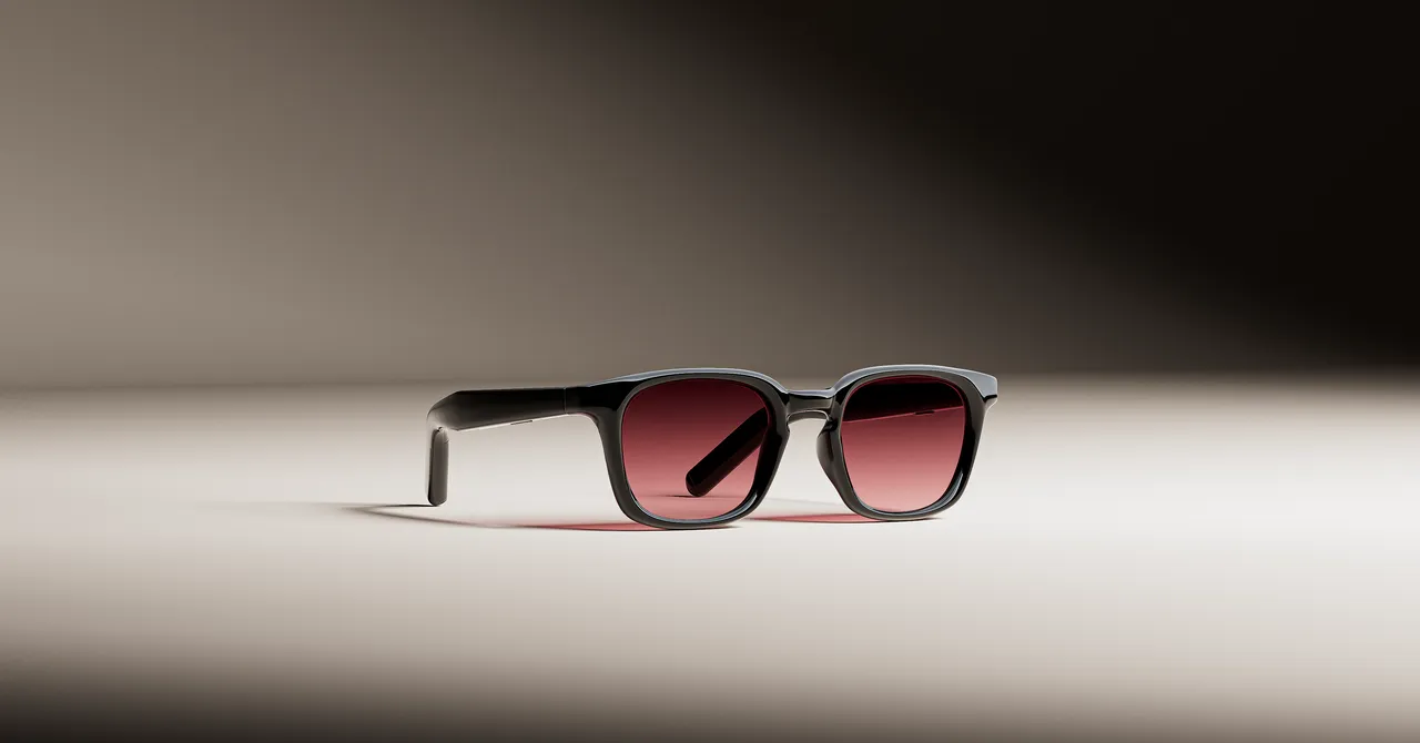 Smart glasses with black frames and tinted lenses on a neutral background.