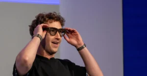 Individual wearing smart glasses and an Apple Watch, adjusting the glasses with both hands, neutral background.
