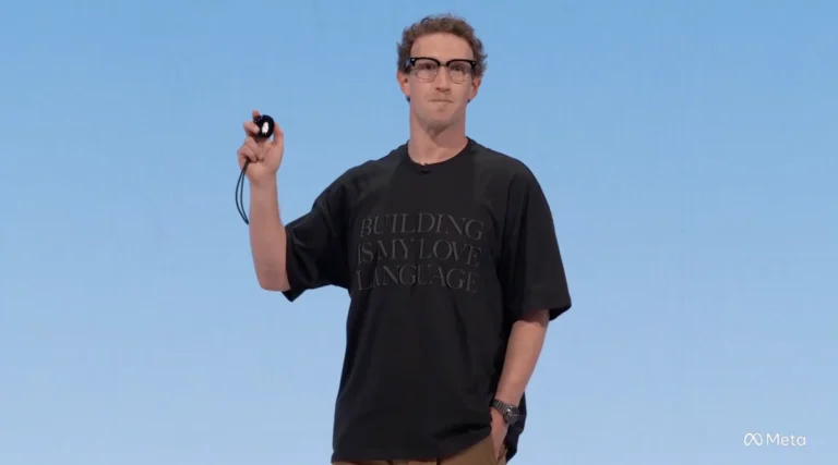 Person holding a small device on stage, wearing a black shirt with "BUILDING IS MY LOVE LANGUAGE" text, Meta logo in corner.