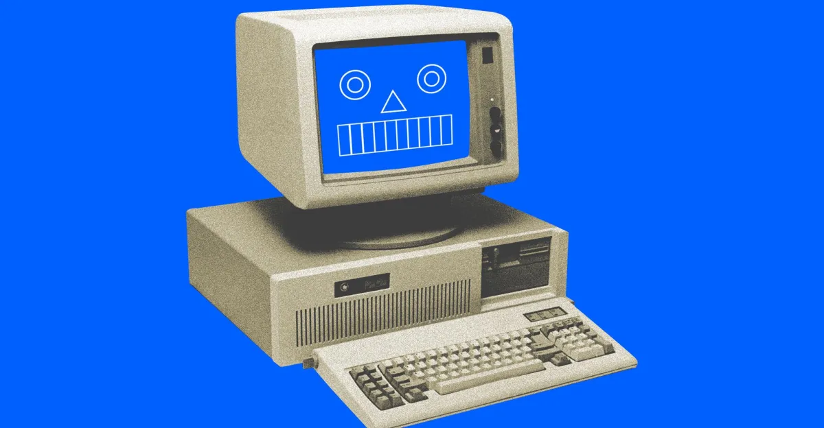 Retro computer with a blue screen displaying a simple robot face, set against a solid blue background.