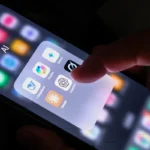 Finger tapping the ChatGPT app icon on a smartphone screen, surrounded by other AI app icons.