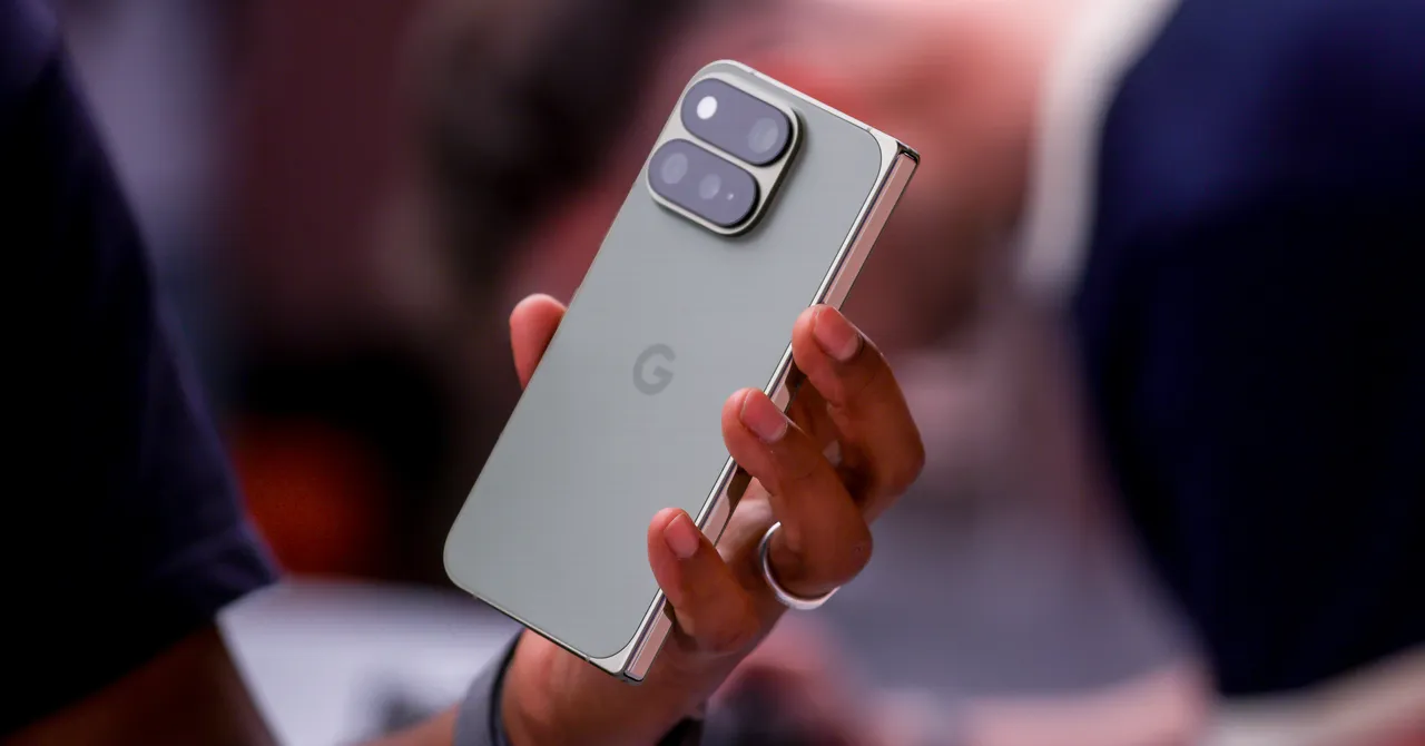 Hand holding a Google Pixel smartphone with dual rear cameras, blurred background.