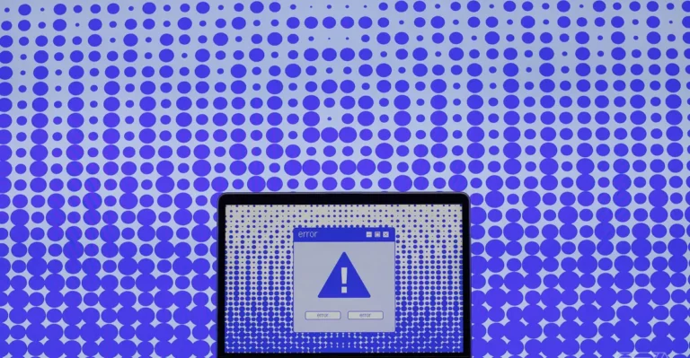 Laptop screen displaying error message with exclamation mark, set against a blue polka dot pattern background