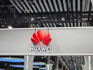 Huawei logo and name on a large white sign, hanging from the ceiling of a modern exhibition space.