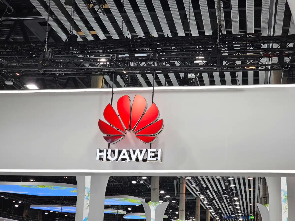 Huawei logo and name on a large white sign, hanging from the ceiling of a modern exhibition space.