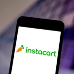 Smartphone displaying the Instacart logo with a carrot icon on a blurred background