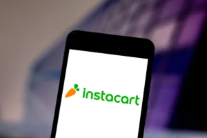 Smartphone displaying the Instacart logo with a carrot icon on a blurred background