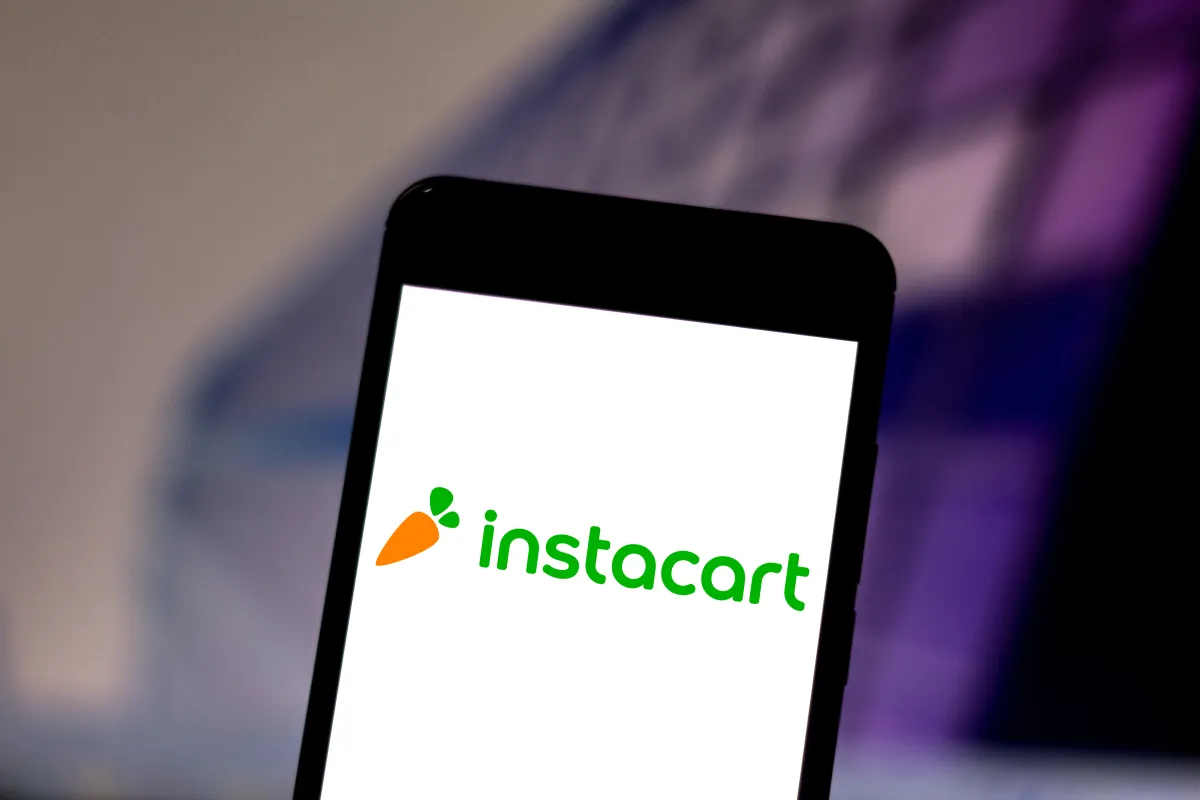 Smartphone displaying the Instacart logo with a carrot icon on a blurred background