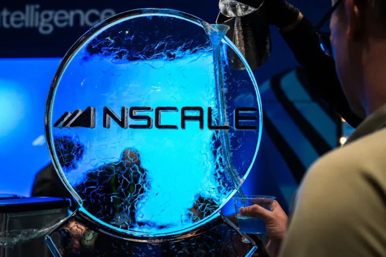 Nscale logo on an ice sculpture, blue lighting, person holding a cup, another pouring liquid from a pitcher.