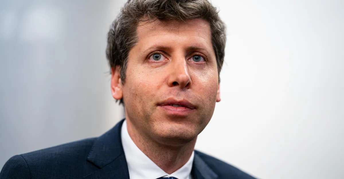 Man in a dark suit looking forward with a neutral expression against a plain background.