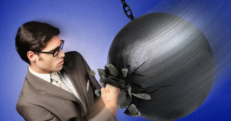 Man in a suit and glasses punches a large wrecking ball, causing cracks, against a blue background.