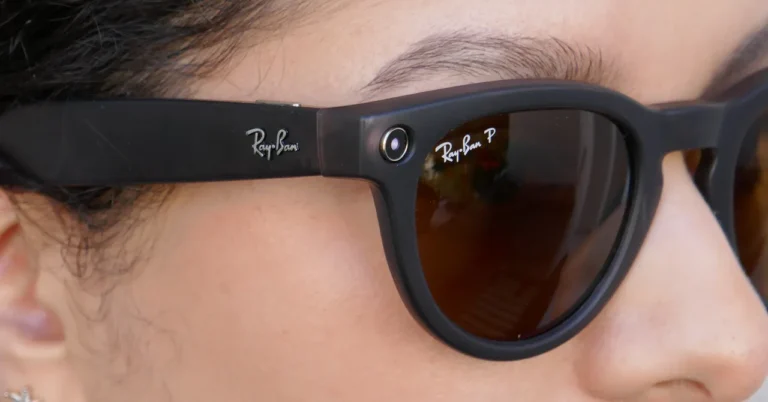 Close-up of a person wearing black Ray-Ban smart glasses with a camera lens on the frame next to the logo.