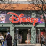 People walking in front of a disney store with large logo and character images on the facade