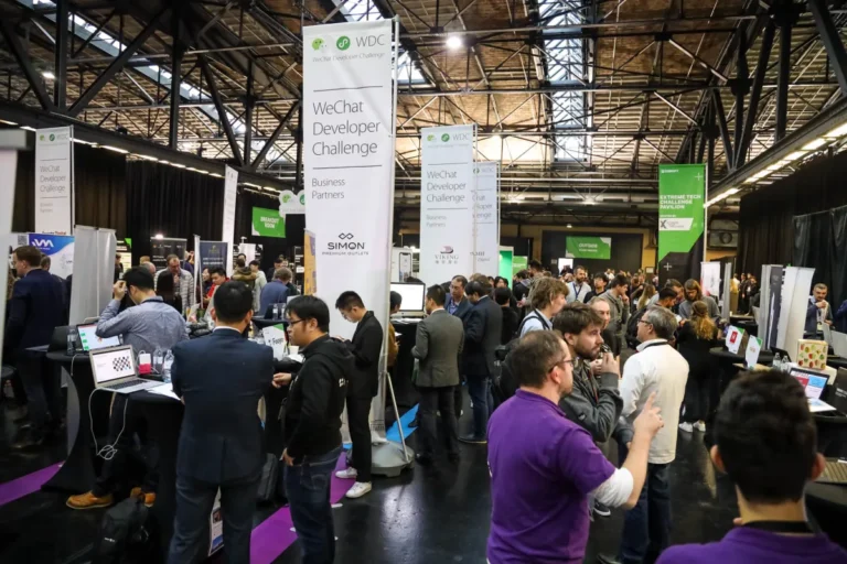 Crowded tech conference floor with people networking and banners for WeChat Developer Challenge and Extreme Tech Pavilion.