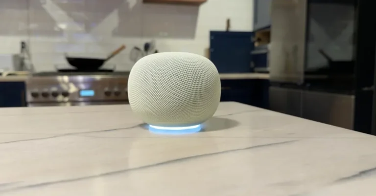Smart speaker with a glowing blue base on a kitchen counter, stove and cabinets in the background.