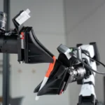 Robotic arm grasping an orange and white marker in a lab setting