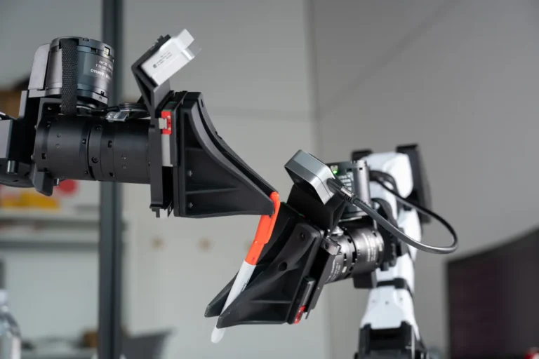 Robotic arm grasping an orange and white marker in a lab setting