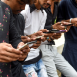 Group of people using smartphones outdoors, focusing on screens
