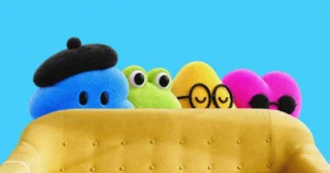 Four colorful, cartoon-like characters peek over a yellow couch against a blue background; each has a different accessory.
