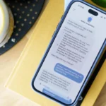 Smartphone on a book displaying a chat with an AI assistant named "dotty mcdotface" discussing task management.