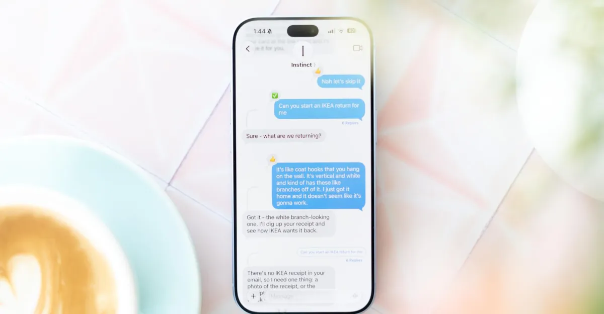 Smartphone displaying a chat with Instinct AI about returning IKEA items, set on a light table next to a latte.