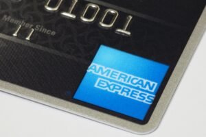 Close-up of an American Express credit card corner showing the logo and embossed numbers.
