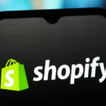 Shopify logo displayed on a smartphone screen with a colorful blurred background.