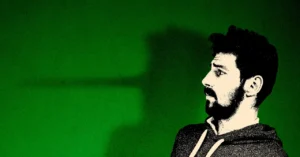 Man with a beard looking anxiously to the side, large nose shadow cast on green background.