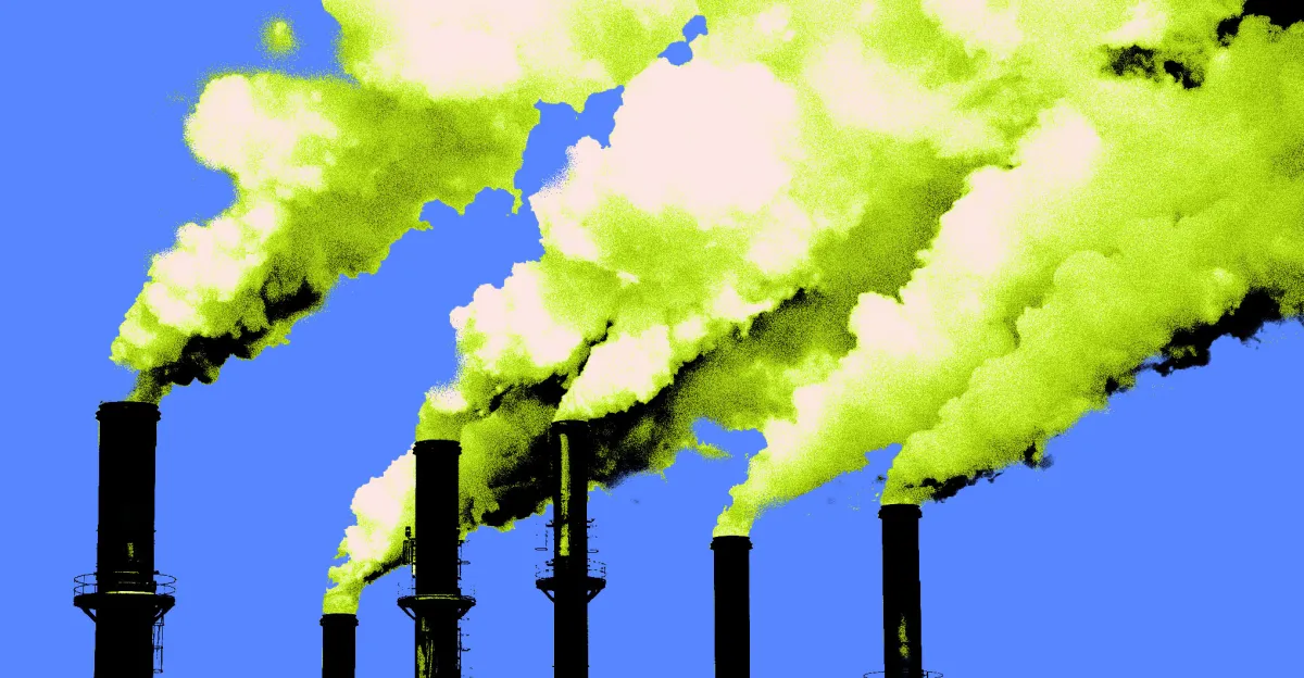 Several smokestacks emitting thick yellow-green smoke against a clear blue sky.