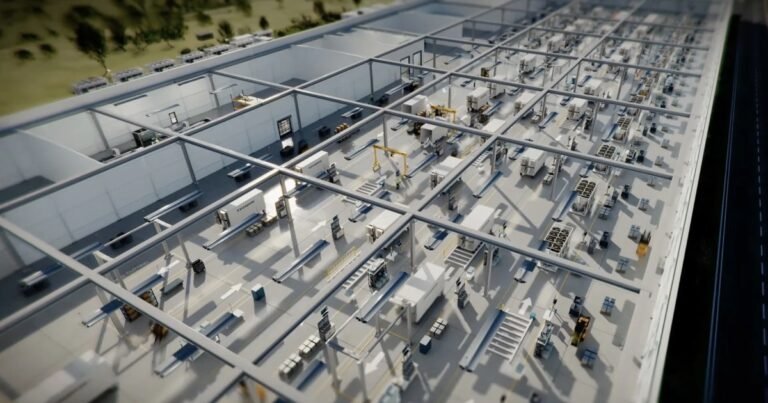 Interior of a large industrial facility with modular units, machinery, and overhead cranes, viewed from above.