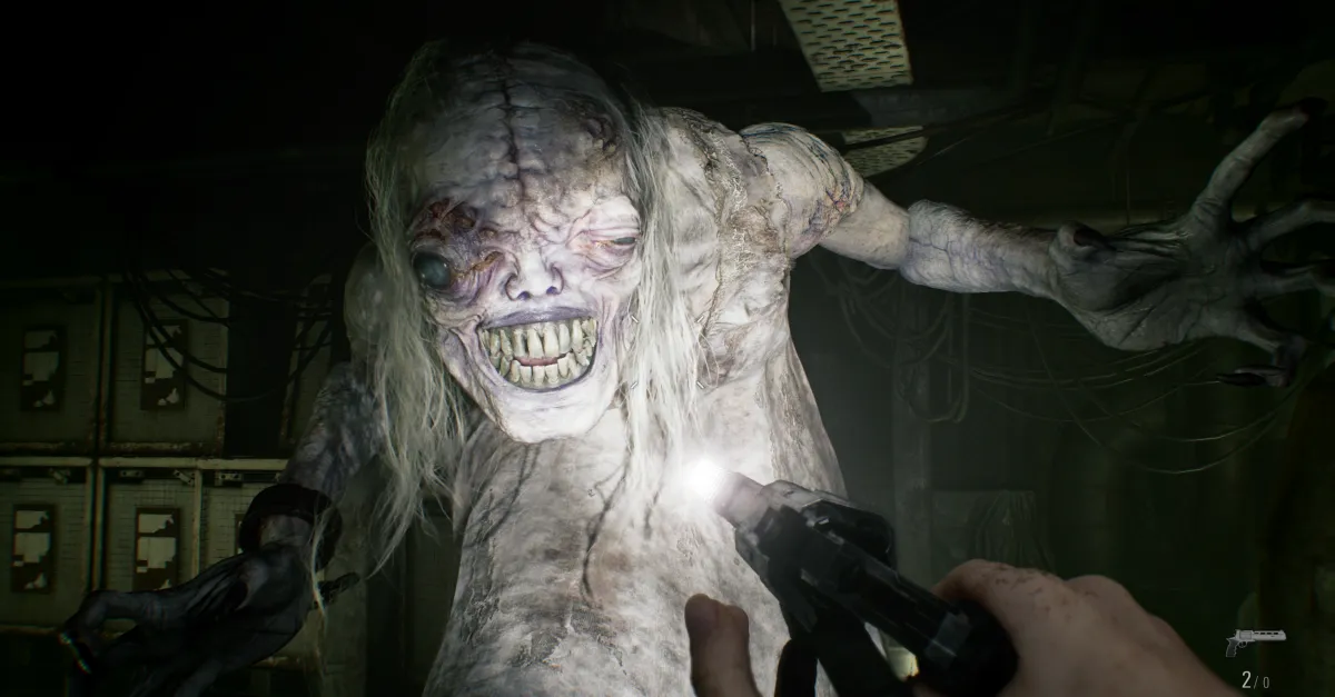 Grotesque creature lunges towards camera in dimly lit room, hand holding a gun aimed at it, wires visible in background