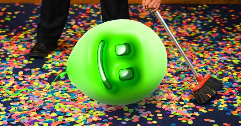 Green smiley balloon on confetti-covered floor, person sweeping with a broom.