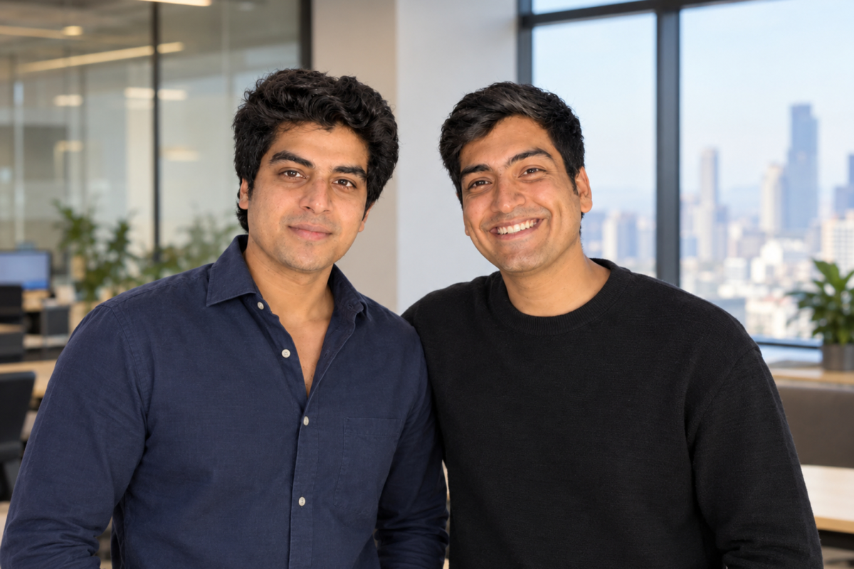 Two men smiling in a modern office with large windows and cityscape background.