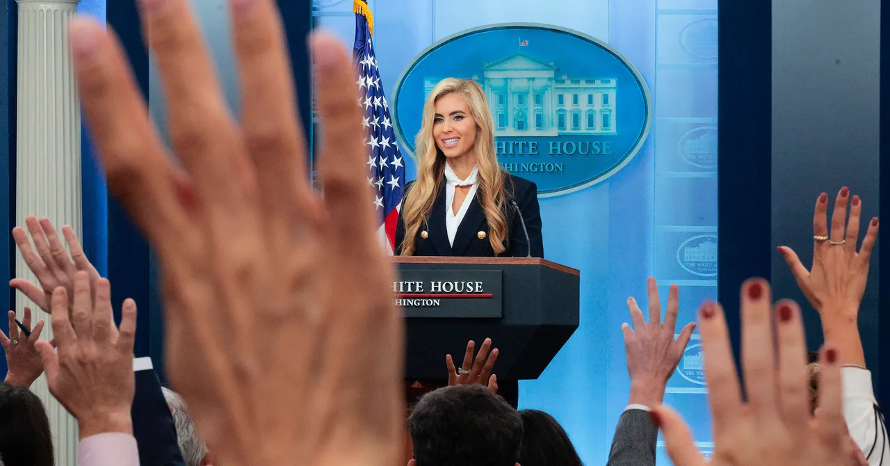 Woman at podium labeled "White House Washington" with raised hands in foreground, US flag and White House emblem behind.