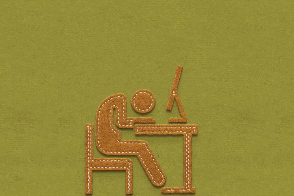 Brown felt figure slumped over a desk with a computer on an olive green background.
