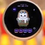 Round device screen displaying pixel art character, battery at 31%, no Wi-Fi, with buttons labeled feed, play, wash, sleep.