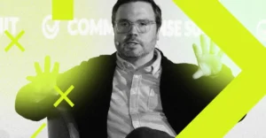 Man speaking on stage with hands raised, wearing glasses and a headset. Neon green graphics overlay the image.