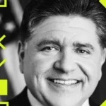 Smiling man in a suit with geometric patterns and bright yellow accents, black and white photo.