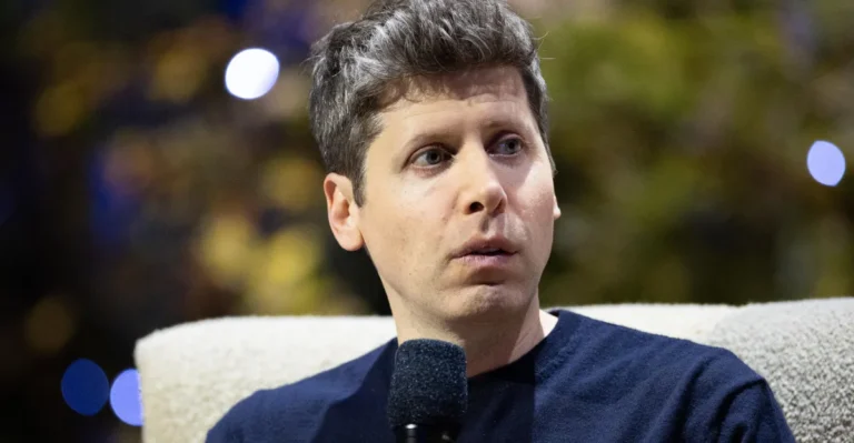 Person holding a microphone, looking to the side, blurred background with lights.
