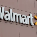 Walmart logo on a brown building wall, featuring white letters and a yellow sunburst symbol.