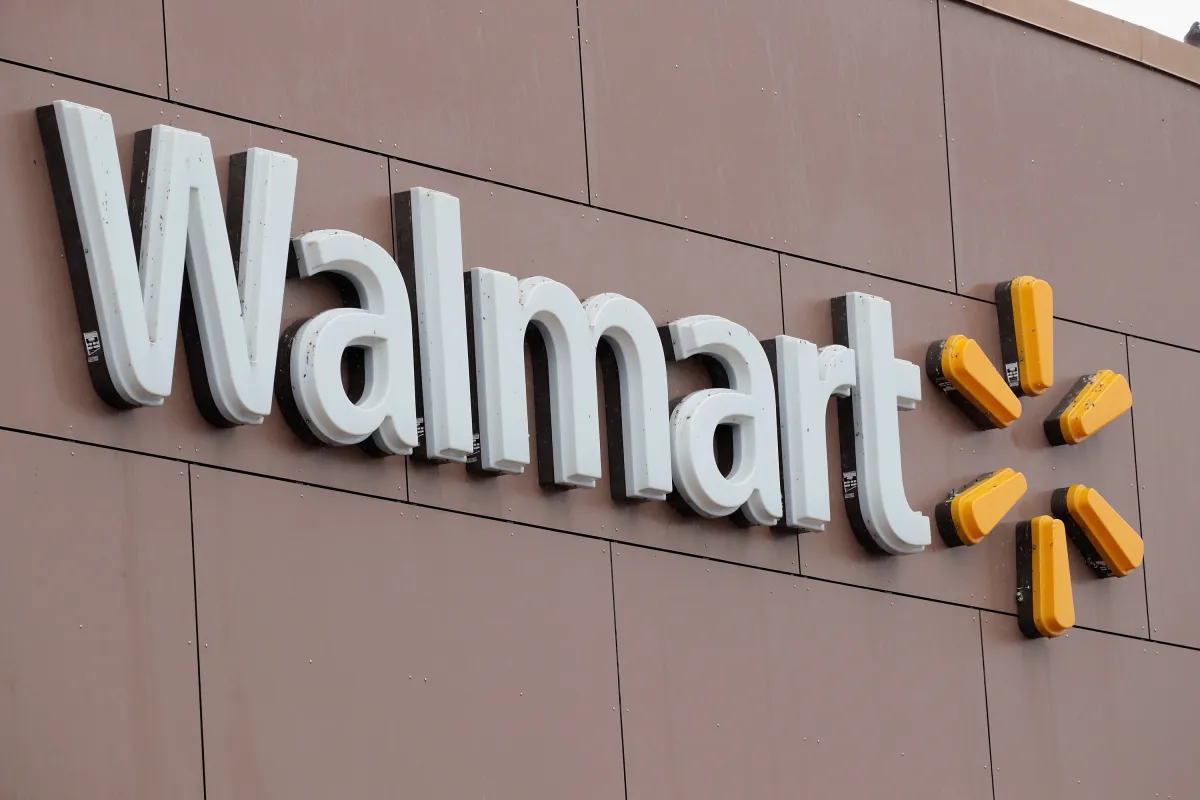 Walmart logo on a brown building wall, featuring white letters and a yellow sunburst symbol.