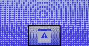 Laptop screen showing a large error alert icon, set against a background of blue dots on a gradient backdrop.