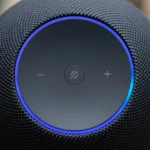 Close-up of a black Amazon Echo speaker with volume controls and a glowing blue ring on top.
