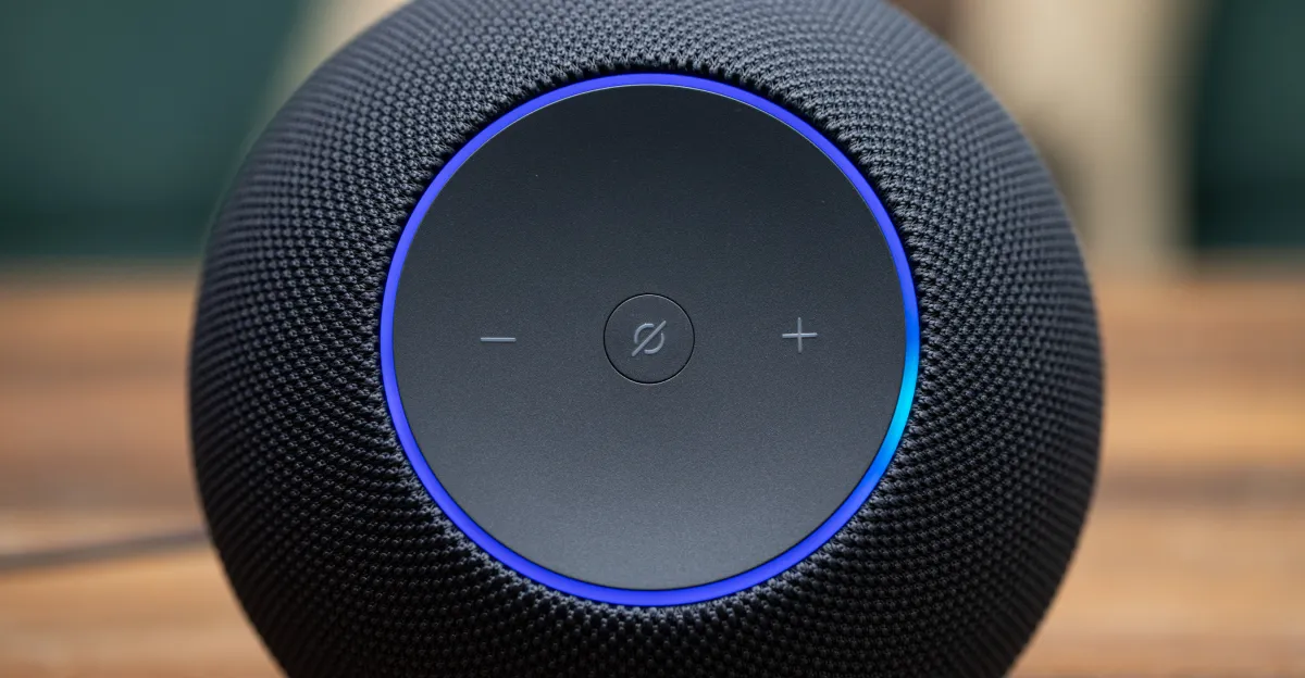 Close-up of a black Amazon Echo speaker with volume controls and a glowing blue ring on top.
