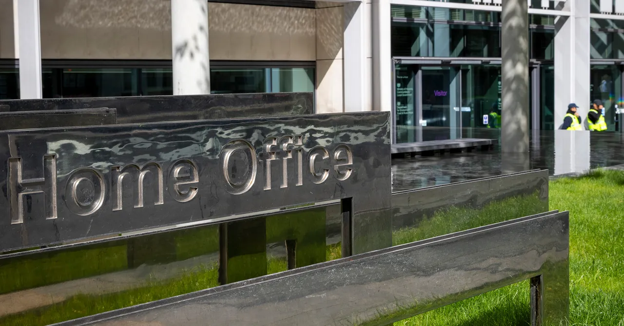 Home Office sign outside a modern building with glass doors and two security personnel in the background.