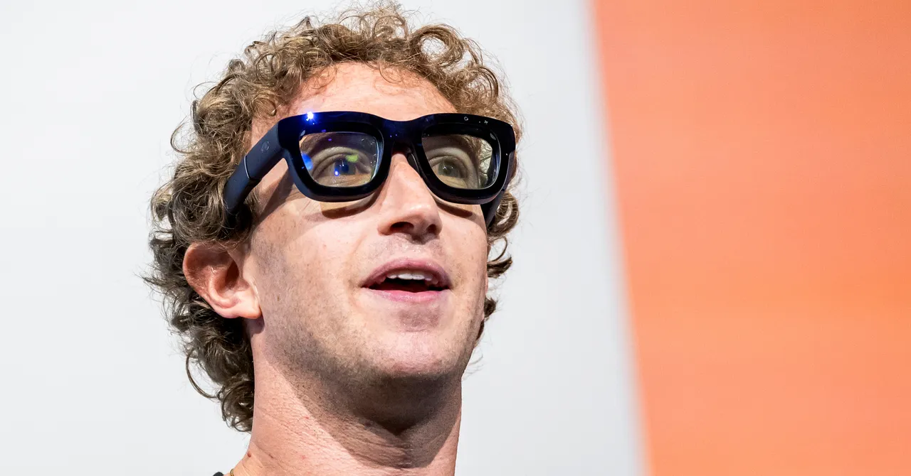 Person with curly hair wearing large black glasses, looking upwards, against a white and orange background.